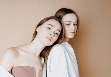 Moda güzellik iki kız kardeş ikiz güzel çıplak kız kameraya arıyorum bej renkli arka plan üzerinde izole modelleri                               