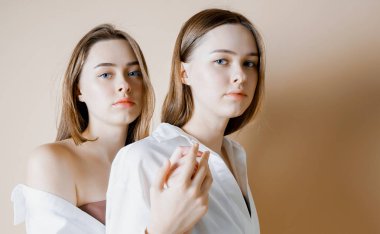 Moda güzellik iki kız kardeş ikiz güzel çıplak kız kameraya arıyorum bej renkli arka plan üzerinde izole modelleri                               