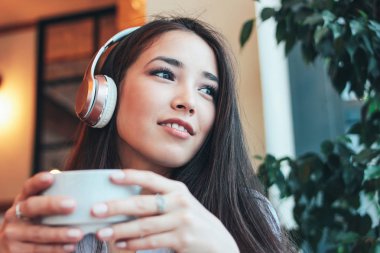 Müzik kulaklık ile kahve veya çay Cafe güzel şirin esmer Asyalı kız gülümseyerek sahiptir