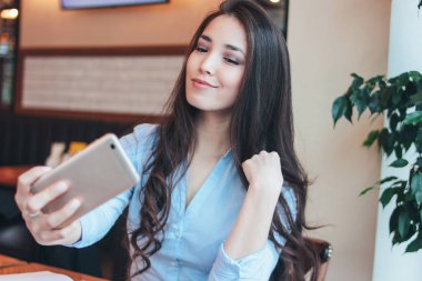 Güzel şirin esmer Asyalı kız alma selfie kafede Smartphone ön kamera üzerinde gülümseyen