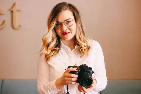 Candid portrait of beautiful blonde girl woman photographer with her camera at work