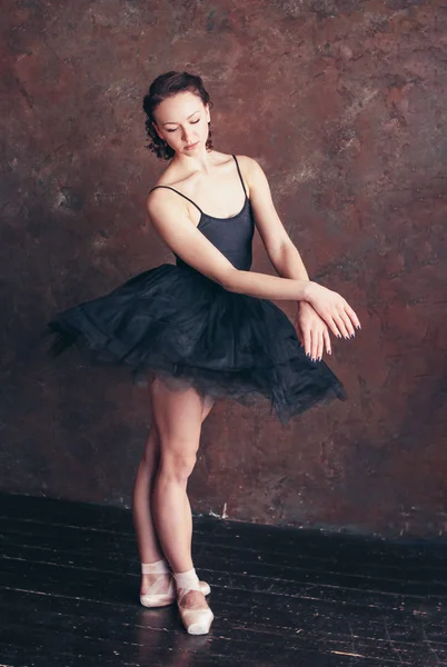 Ballet dancer ballerina in beautiful black dress tutu skirt posing in loft studio