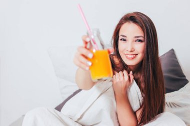 Cam mutlu güzel gülümseyen Asyalı kız genç kadın, elinde portakal suyu sağlıklı rahat sabah