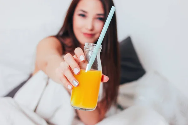 Orange juice in glass jar in hand of happy beautiful smiling asian girl young woman, healthy cozy morning
