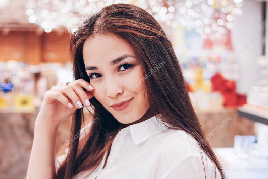 The beautiful long hair asian smiling girl young woman in shop supermarket of cosmetics, perfumes, duty free