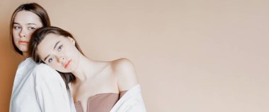 Moda güzellik modelleri iki kız kardeş İkizler güzel çıplak kız izole bej renkli arka plan üzerinde afiş