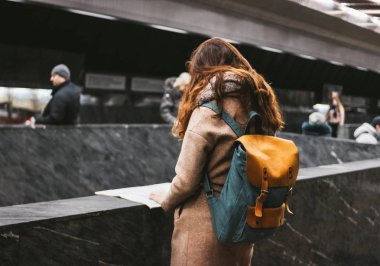 Genç kadın kıvırcık kırmızı kafa kız Gezgin sırt çantası ve harita ile metro