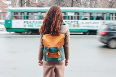 Genç kadın kıvırcık kırmızı kafa kız Gezgin şehir sokak tramvay önünde sırt çantası ile