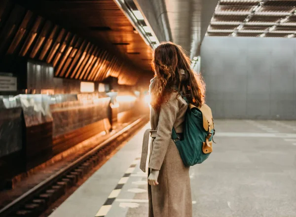 Молодая женщина кудрявая рыжая голова девушка путешественник с рюкзаком и карта в метро станции — стоковое фото