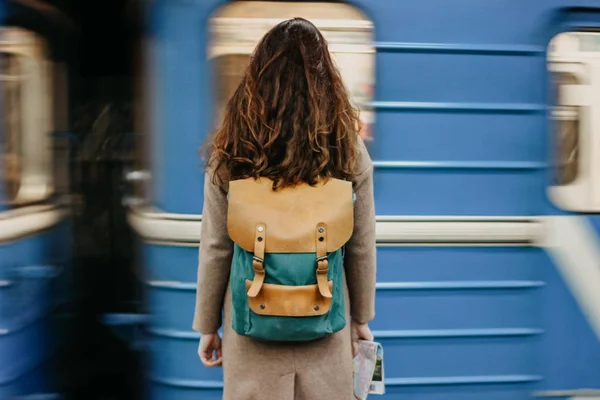 Молодая женщина кудрявая красная голова девушка путешественник с рюкзаком и карта в метро станции перед поездом — стоковое фото