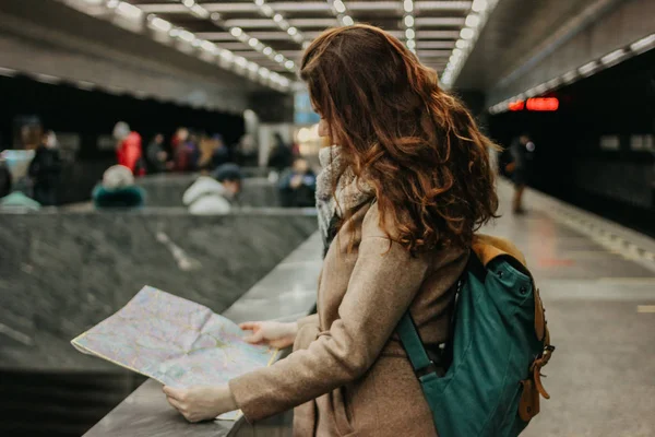 Молодая женщина кудрявая рыжая голова девушка путешественник с рюкзаком и карта в метро — стоковое фото