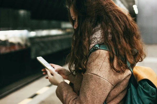 Jeune femme bouclée rousse tête fille voyageur avec sac à dos en utilisant mobile dans le métro — Photo
