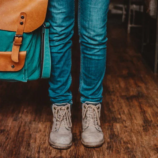Foto de corte de jovem mulher pés menina viajante em jeans e botas com mochila dentro de casa — Fotografia de Stock