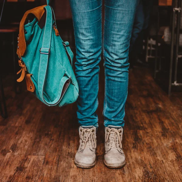 Foto de corte de jovem mulher pés menina viajante em jeans e botas com mochila dentro de casa — Fotografia de Stock