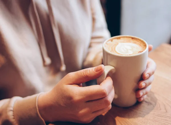 Чашка кофе капучино в женских руках в кафе, закрыть — стоковое фото