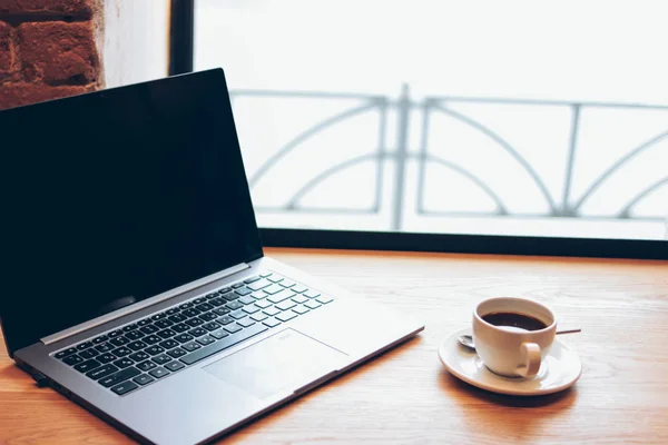 Abierto portátil y una taza de café en la mesa en el café, freela — Foto de Stock