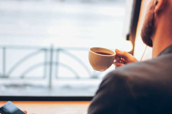 The man using mobile phone, sitting with coffee at cafe