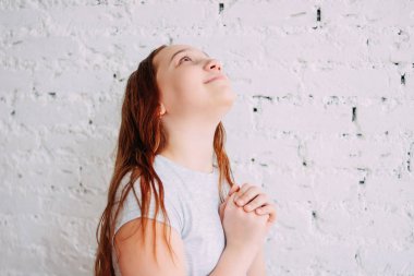 Güzel büyüleyici Redhead gülümseyen genç kız beyaz tuğla duvar üzerinde izole bir dilek yapma