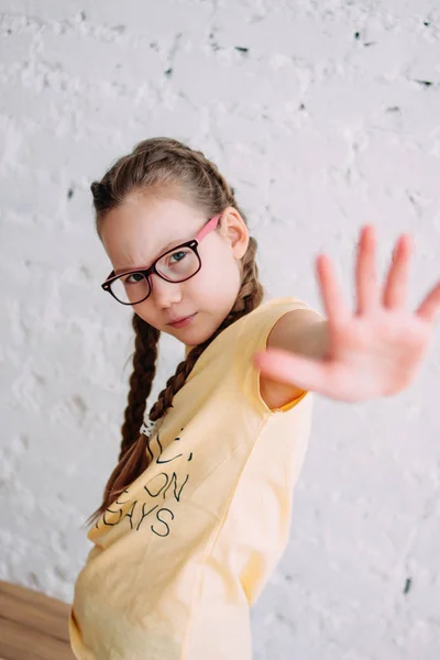 Sad long hair tweens girl in glasses pulling hand towards camera on white wall background — Stock Photo, Image