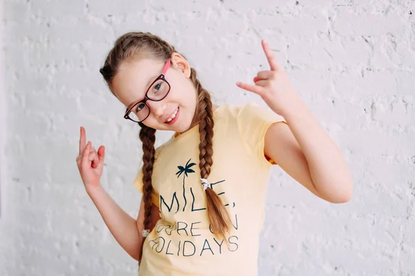 Retrato de linda chica preadolescentes en camiseta amarilla con divertidas coletas en el fondo de la pared de ladrillo blanco — Foto de Stock