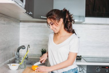 Mutlu gülümseyen güzel uzun saçlı Asyalı kız genç kadın limon mutfağında keser.