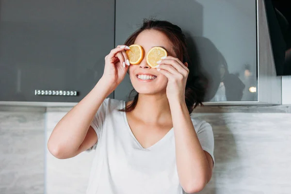 Gelukkig lachend grappig mooi meisje jonge vrouw ogen sluiten door lemon in keuken — Stockfoto