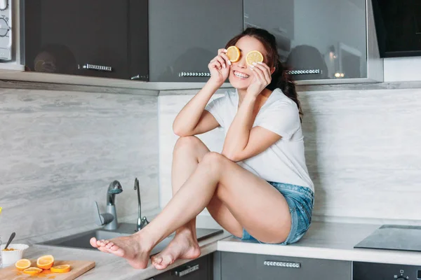 Gelukkig lachende mooie lange haren meisje grappige jonge vrouw met citroen in keuken — Stockfoto