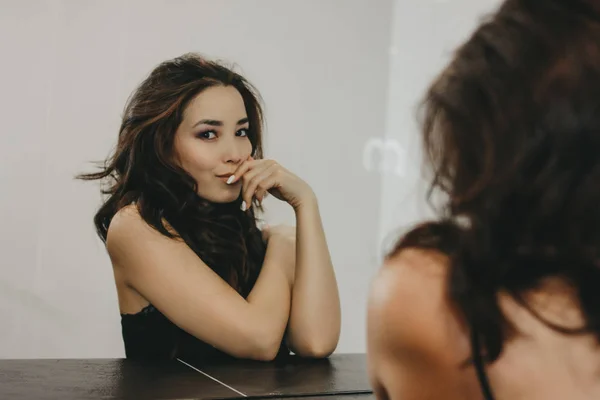 Sensuele mooie Aziatische jonge vrouw met donkere lange haren kijken naar camera voor spiegel — Stockfoto