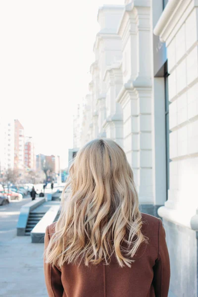 Стильная модная женщина в пальто с кудрявыми светлыми волосами на улице — стоковое фото