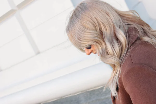 Stylowa modna kobieta uśmiechnięta ubrana w beżowy płaszcz z Kręcone blond włosy na ulicy — Zdjęcie stockowe