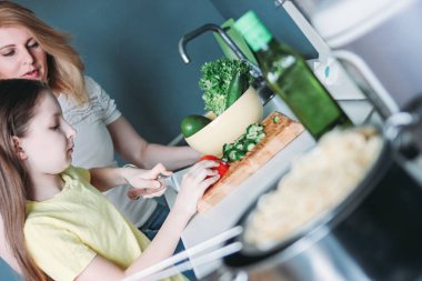 Ara kız ve annesi evde mutfakta sebze salatası yapma