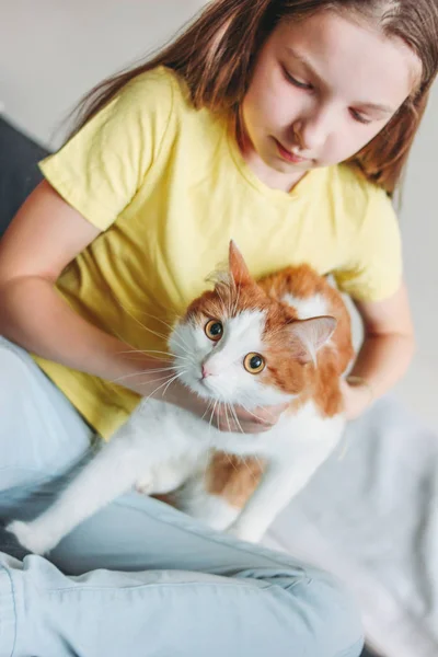 Linda chica adolescente en camiseta amarilla con su gato blanco en casa — Foto de Stock