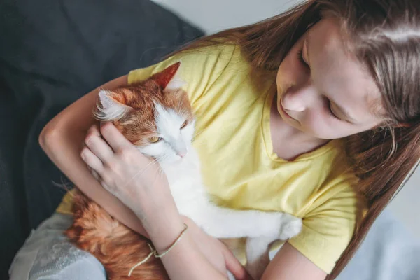 Linda chica adolescente en camiseta amarilla con su gato blanco en casa — Foto de Stock