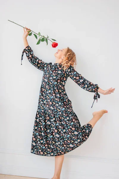Bela romântica jovem loira no vestido com rosa vermelha no fundo walll branco, retrato de comprimento total — Fotografia de Stock