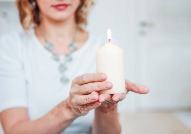 Mehendi yanan mum tutan beyaz giyimli sarışın genç kadın