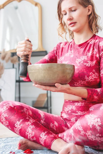 Молодая женщина играет на латунной тибетской поющей чаше. Звуковая терапия и медитация — стоковое фото