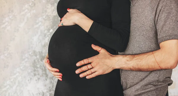 Oříznout fotografii těhotné mladé ženy v černých šatech s manželem. Autentický neobyčejný pár, rodina čekající na dítě — Stock fotografie