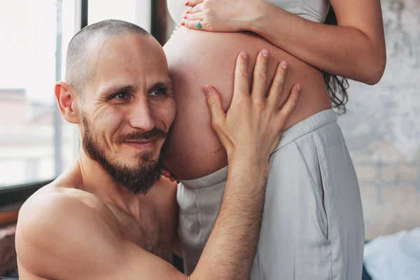 Šťastný budoucí otec poslouchá dětské břicho své ženy. Autentický pár, rodina čekající na dítě — Stock fotografie