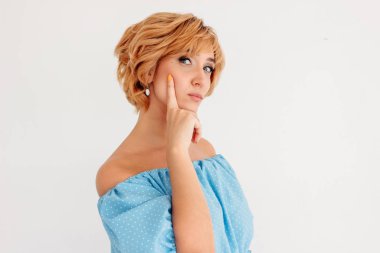 Genç, çekici, sarışın, kısa saçlı, mavi elbiseli, beyaz arka planda soyutlanmış bir kadın.