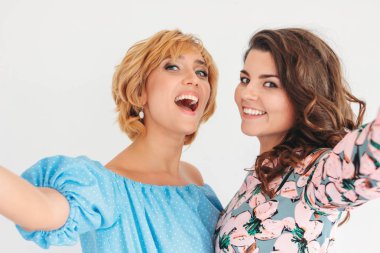 Beyaz arka planda izole ön kamera selfie yapma yaz elbise iki güzel büyüleyici genç kadın