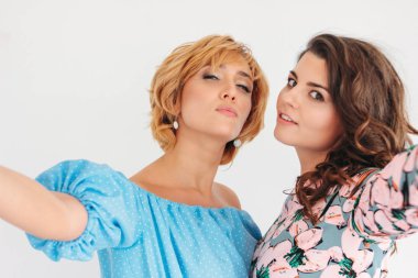 Beyaz arka planda izole ön kamera selfie yapma yaz elbise iki güzel büyüleyici genç kadın