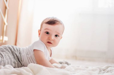 Sevimli küçük bebek erkek 6 ay evde beyaz battaniye üzerinde kamera bakıyor