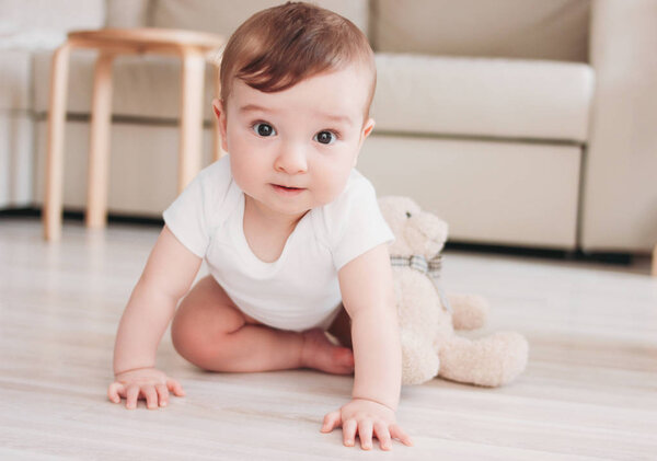 Charming little baby boy 6 months smiling and looking at the camera in home
