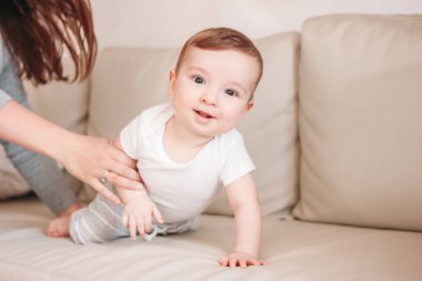 Sevimli küçük bebek erkek bebek evde kanepede mutlu anne ile 6 ay, samimi portre kadar yakın