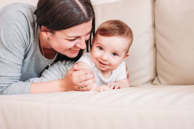 Sevimli küçük bebek erkek bebek evde kanepede mutlu anne ile 6 ay, samimi portre kadar yakın