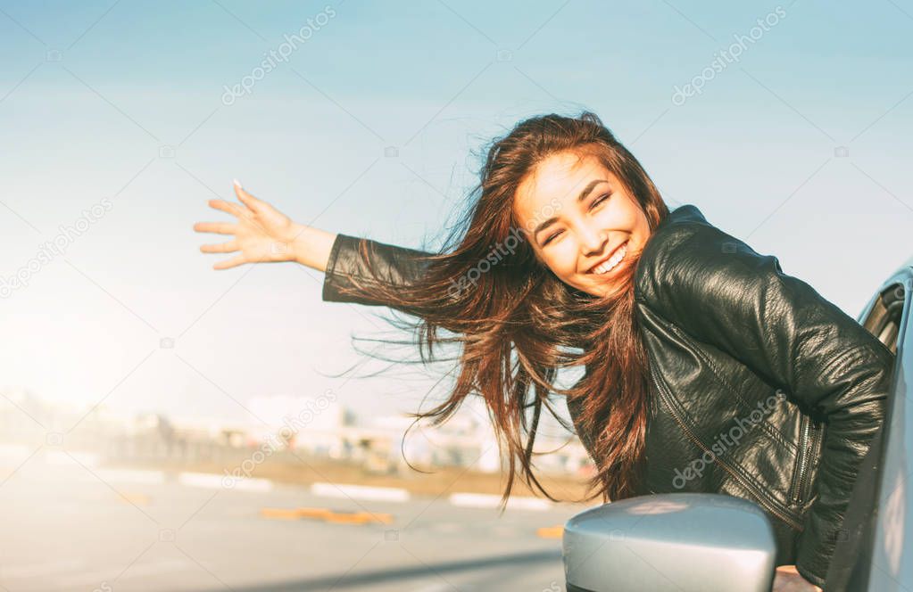 Happpy beautiful charming brunette long hair young asian woman in black leather jacket in car window at sunset