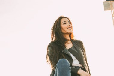 Gün batımında siyah deri ceket güzel büyüleyici esmer uzun saç mutlu asya kız