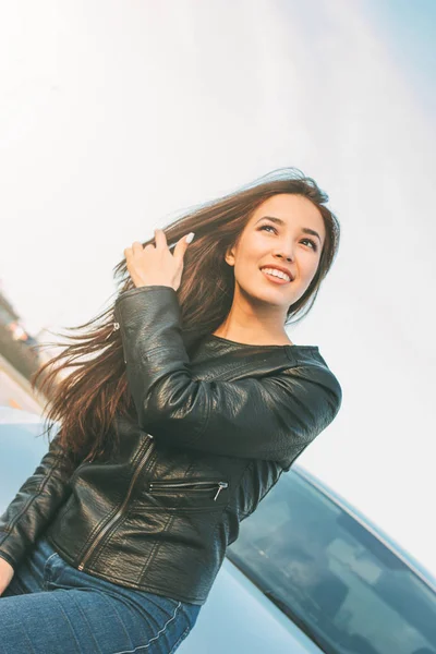 Happpy mooie charmante brunette lang haar jonge Aziatische vrouw in zwart lederen jas in de buurt van haar auto — Stockfoto