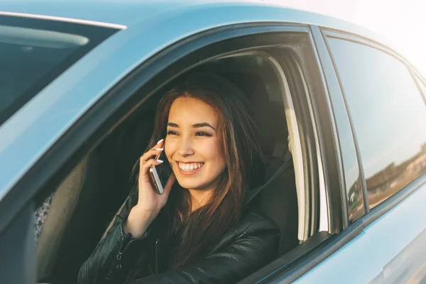 Mooie brunette lang haar jonge Aziatische vrouw rijden en spreken door mobiele telefoon — Stockfoto
