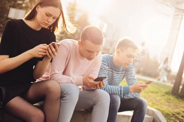 Um grupo de jovens amigos adolescentes graves usando celular na rua da cidade — Fotografia de Stock